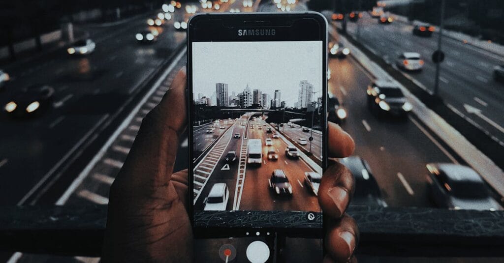 Capturing the vibrant twilight cityscape of Sao Paulo through a mobile phone lens on a bustling highway.